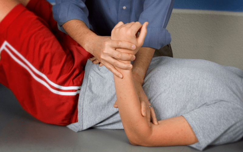 person laying on their back receiving physical therapy for their elbow